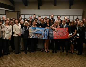CIEE staff, host employers, and community partners gather for a group photo during the BridgeUSA Celebration Tour event in Park City, Utah, holding a BridgeUSA Celebration banner.