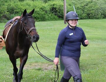 Venla S. of Finland leads a horse at a summer camp in Connecticut.