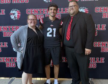Host couple Shannon and Jarred Johnston pose with exchange student Cem M. of Germany after a football game.