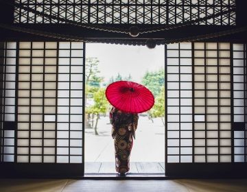 Woman in kimono with umbrella standing in doorway