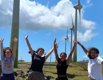 students jump abroad by wind turbines
