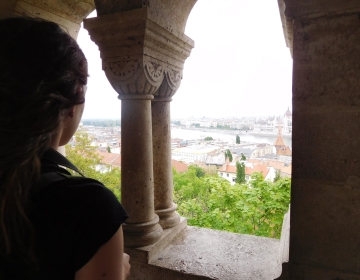 Pensive woman looking out columned window at Budapest