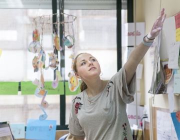 Teacher gesturing to board in classroom while teaching class