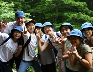 Young adult and Japanese students in group selfie outside