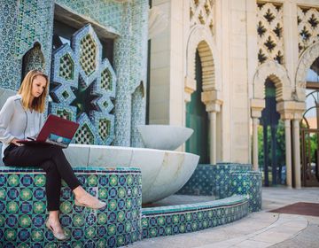 Seville student intern working on laptop by a fountain
