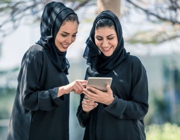 Women in United Arab Emirates looking at a tablet outside