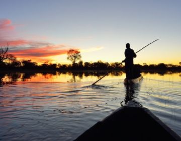 gaborone man on paddle boat in river at sunset