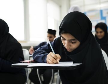 Student in classroom in United Arab Emirates writing at desk