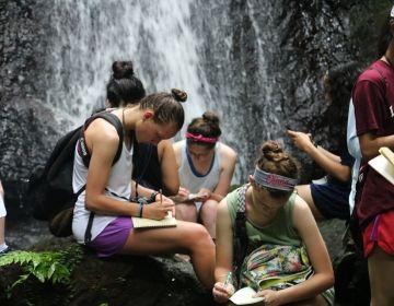 High school students journaling by a waterfall in Monteverde