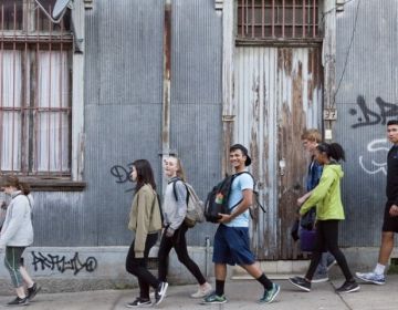 Photo of Mohamed Kilani smiling and walking with other students in front of a wall in Chile