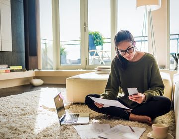 Young woman on her phone with her laptop out before her