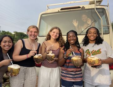 students posing with coconuts in front of a truck in Legon