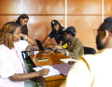 students standing around a laptop smiling