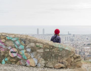 Student in red hat looking down at city skyline on hike