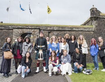 High school students studying abroad posing with bagpiper