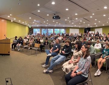 a wide shot of a large group people in a classroom