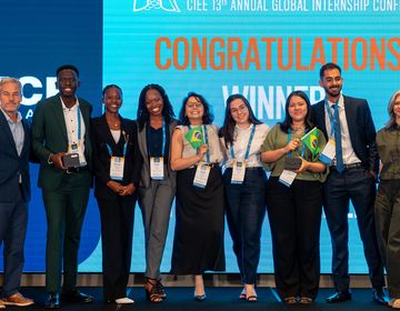 A group of 10 people standing on stage holding awards 