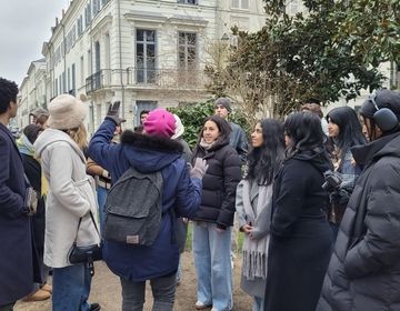 students standing in a group in Paris streets looking at a tour guide