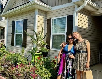 A host mom and daughter pose in front of their house.