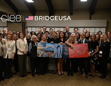 CIEE staff, host employers, and community partners gather for a group photo during the BridgeUSA Celebration Tour event in Park City, Utah, holding a BridgeUSA Celebration banner.