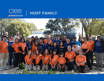 A group of 45 people standing in blue or orange t-shirts that say "CIEE". Above, a header says "CIEE | BridgeUSA" and "Host Family"