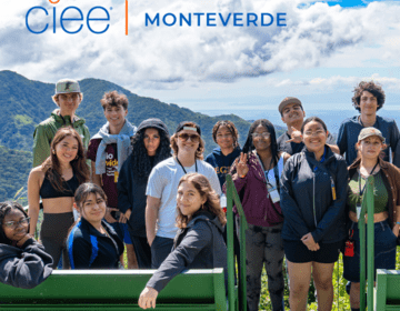 A group of 13 students standing in front of a mountain range