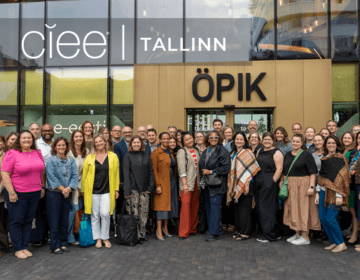A group of 21 people stand together smiling out front of a newer looking building with "OPIK" as a logo on the building. Top left is "CIEE Tallinn" label.