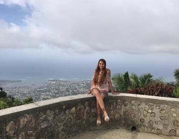 Octavia Tey sits on a stone overlook above Santiago de los Caballeros, Dominican Republic, during her CIEE study abroad experience.