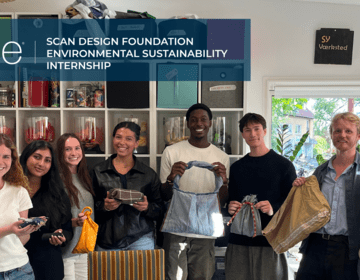 Group photo of eight participants in a sustainable fashion workshop, proudly displaying handmade bags around a craft table covered with fabric scraps and sewing tools.