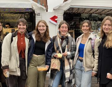Group of female study abroad students pose at Christmas market in Toulouse, France