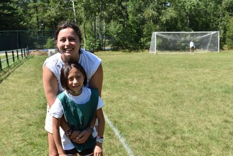 Counselor and student hugging on soccer field