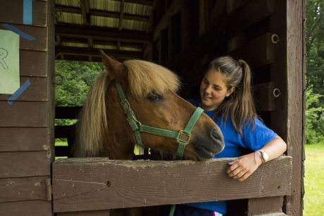 Counselor and horse in stable at camp