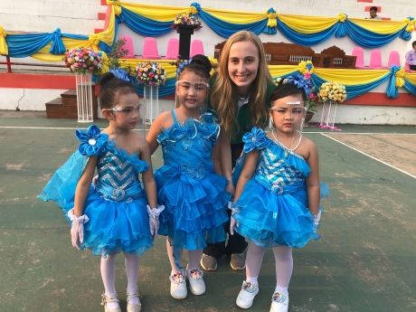 Young female teacher with Thai students in costumes at festival