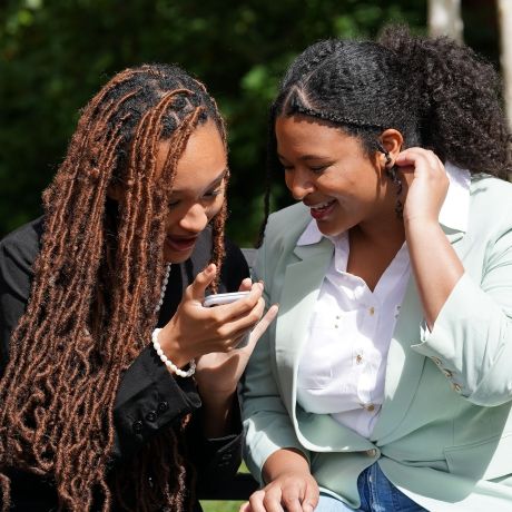 students looking at phone outside sunny day