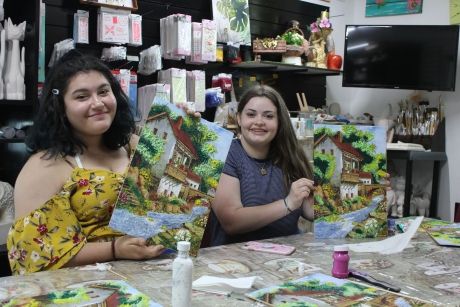 High school students holding up their paintings in art class