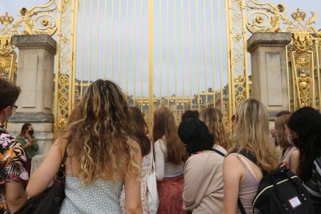 Group of high schoolers in front of the gilded gate of Versailles in Paris