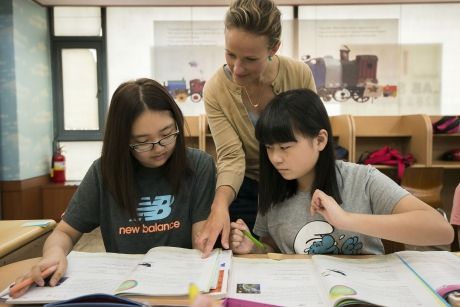 Teach in South Korea teacher helping students in classroom