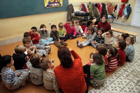 Kids huddled on the floor with their teachers in classroom in Spain
