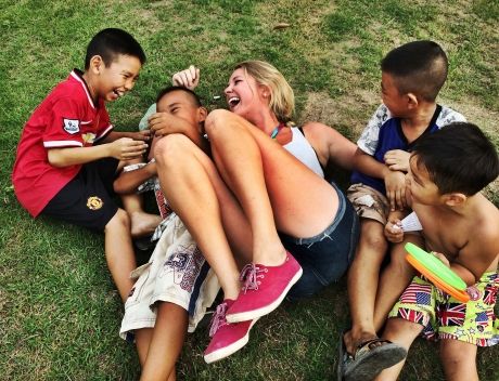 Teacher and students rolling in the grass