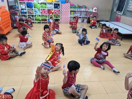 Thai kids in class holding up national flags
