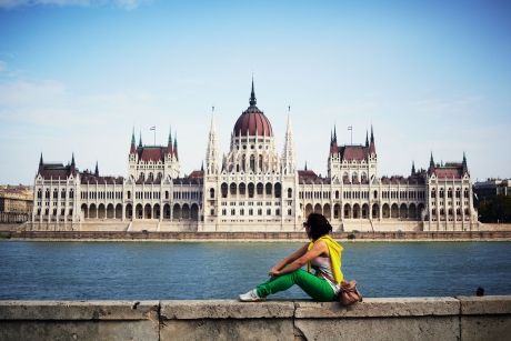 Woman sitting by the water facing Parliament building in Budapest