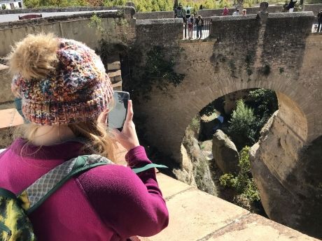 Student taking photo of old bridge in Ronda, Spain
