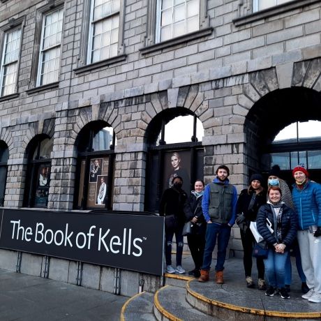 dublin students standing next to sign that reads The Book of Kells