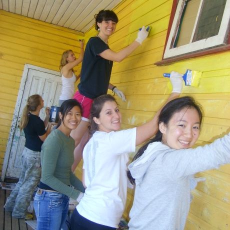 santiago ch students volunteering to paint a building exterior