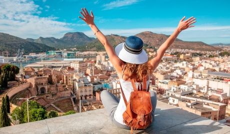 spain woman in murica sitting above city with her hands up