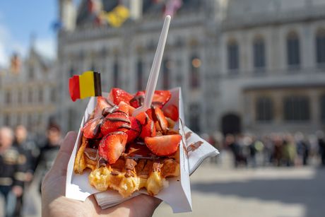 Traditional Belgian waffle dessert with chocolate and fruits and a flag.