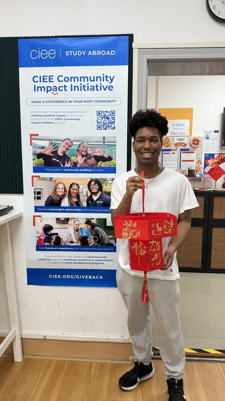 Student stands next to CIEE Community Impact Initiative banner