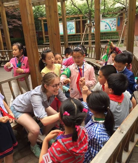 Teacher kneeling outside with students in China