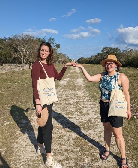 Two women with CIEE totes holding up their hands on a path in the Yucatan