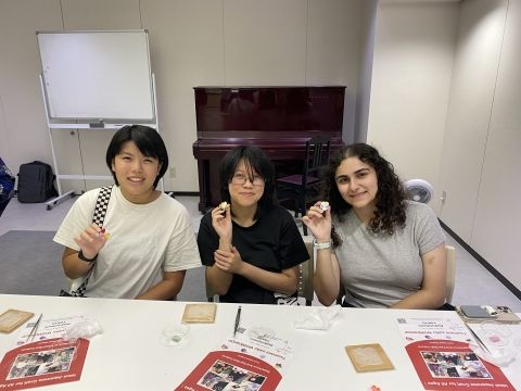 Students holding their flowers made with Tsumami-zaiku technique